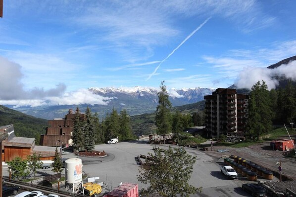 A mountainous town with a parking area, buildings, and a view of snow-capped peaks.