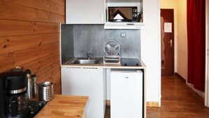 Une petite cuisine équipée d’un four à micro-ondes, d’un évier et d’un petit réfrigérateur.