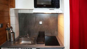 Cocina compacta con fregadero, estufa y microondas.