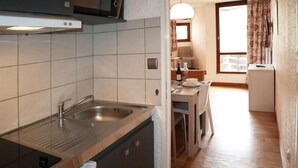 A compact kitchen with a sink, stove, and a dining area with a table and chairs. - 100m from ski slopes, 4th floor, balcony, tv, ski locker, 25m², Les Orres (Les Orres)