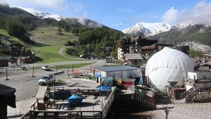 A mountainous village with a large dome structure, a winding road, and buildings with visible signage. - 100m from resort center, 4th floor, tv, ski locker, 20m², Les Orres (Les Orres)