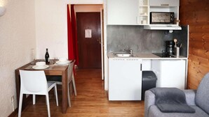 A compact living space with a dining area, kitchenette, and a grey sofa. - 100m from resort center, 4th floor, tv, ski locker, 20m², Les Orres (Les Orres)