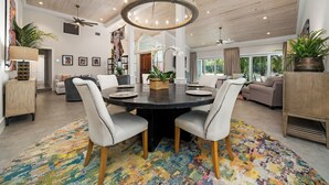 A spacious living room with a round dining table, two sofas, and a ceiling fan. - Orchid House (Paradise Island)
