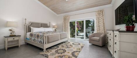 A bedroom with a bed, nightstands, a dresser, a ceiling fan, and a view through a glass door to the outside.