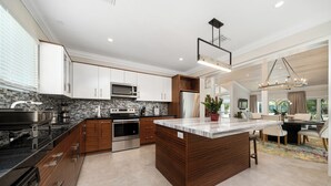 A modern kitchen with a central island, stainless steel appliances, and wooden cabinetry. - Orchid House (Paradise Island)