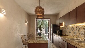 Une cuisine moderne dotée d’un plan de travail en granit, de meubles en bois foncé, d’un pare-feu décoratif et d’un luminaire suspendu.