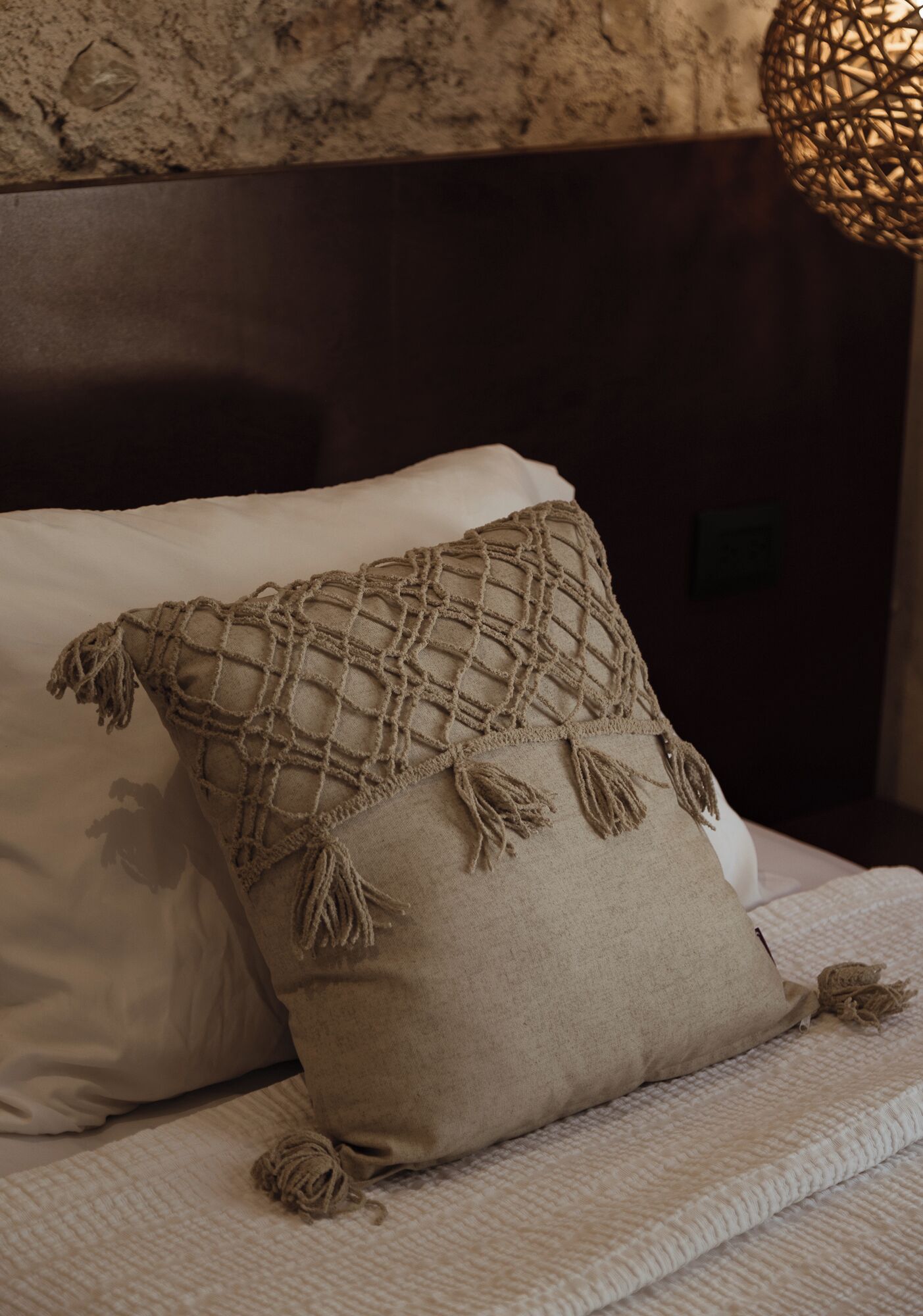 A bed with two pillows, one plain and one with a netted cover.