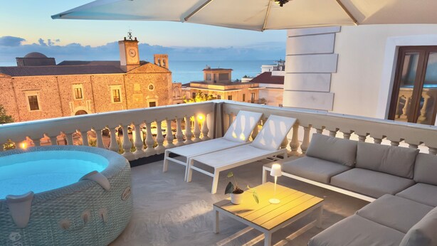 Une terrasse sur le toit avec une piscine, des chaises longues, un canapé et une table.
