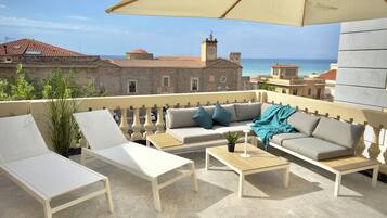 Relax on the spacious outdoor terrace with a sofa, lounge chair, and table, taking in the breathtaking views of the coastal city.