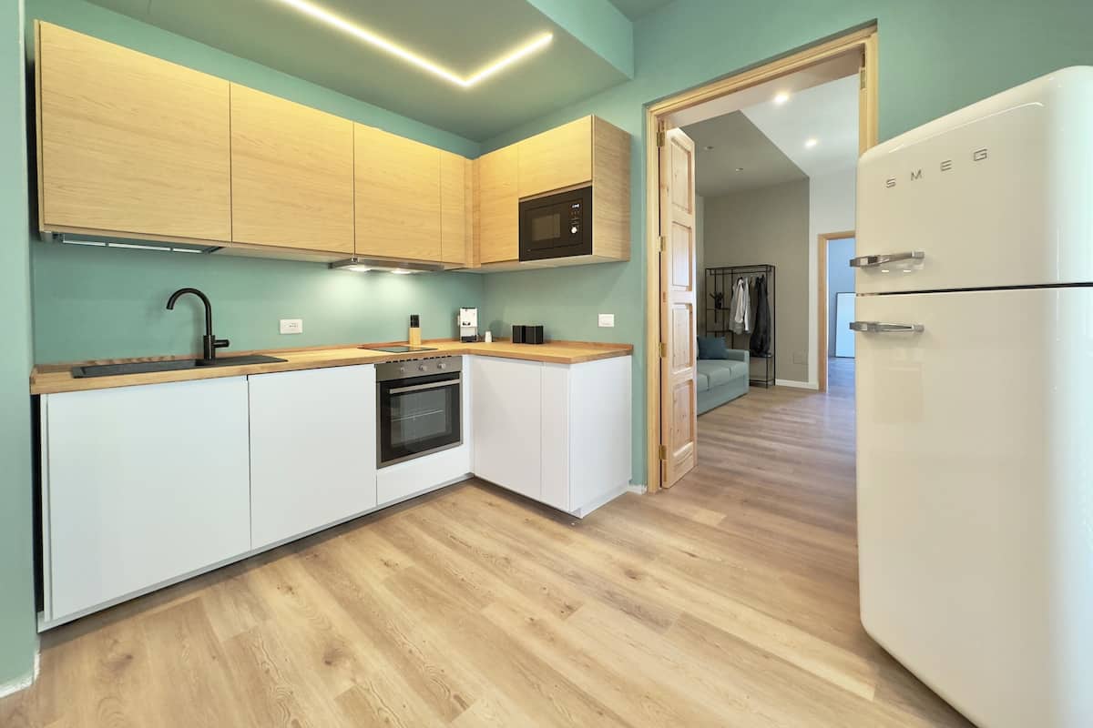 Een moderne keuken met houten kastjes, een inbouwoven en een witte koelkast.