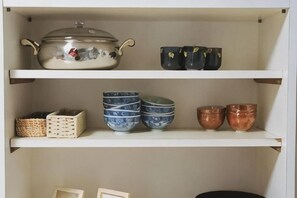 Une étagère avec un grand pot, plusieurs bols et un panier.