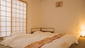 Ein Zimmer mit einem Bett, einem Fenster mit Gittermuster und einem an der Wand hängenden Bild.