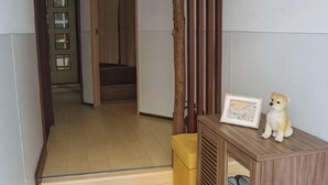 Ein Zimmer mit einem Holzschrank, einem kleinen Tisch mit einem gerahmten Bild und einer Tür zu einem weiteren Raum.