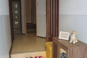 Een kamer met een houten kast, een klein tafeltje met een lijst eromheen, en een deur naar een andere kamer.