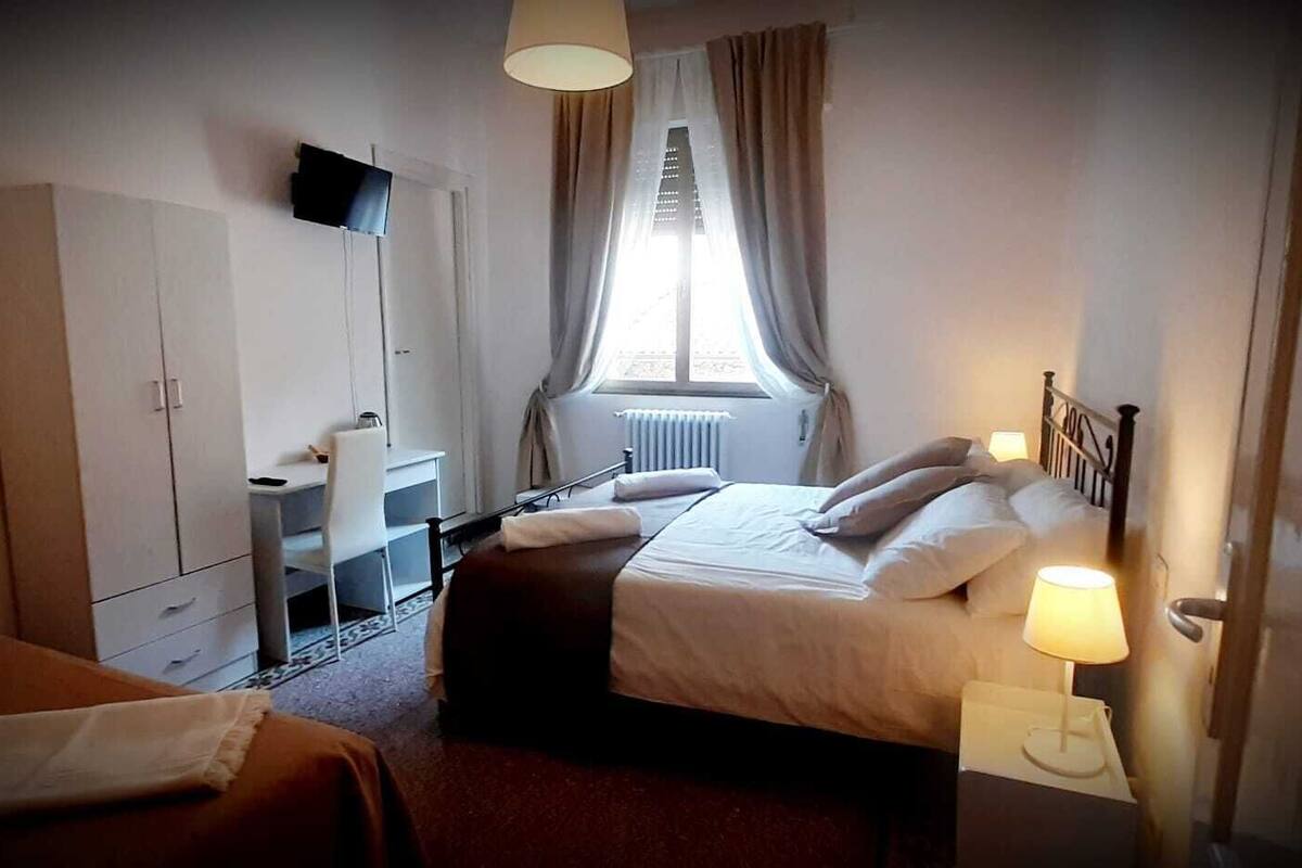 A hotel room with two beds, a desk, a chair, and a TV mounted on the wall.