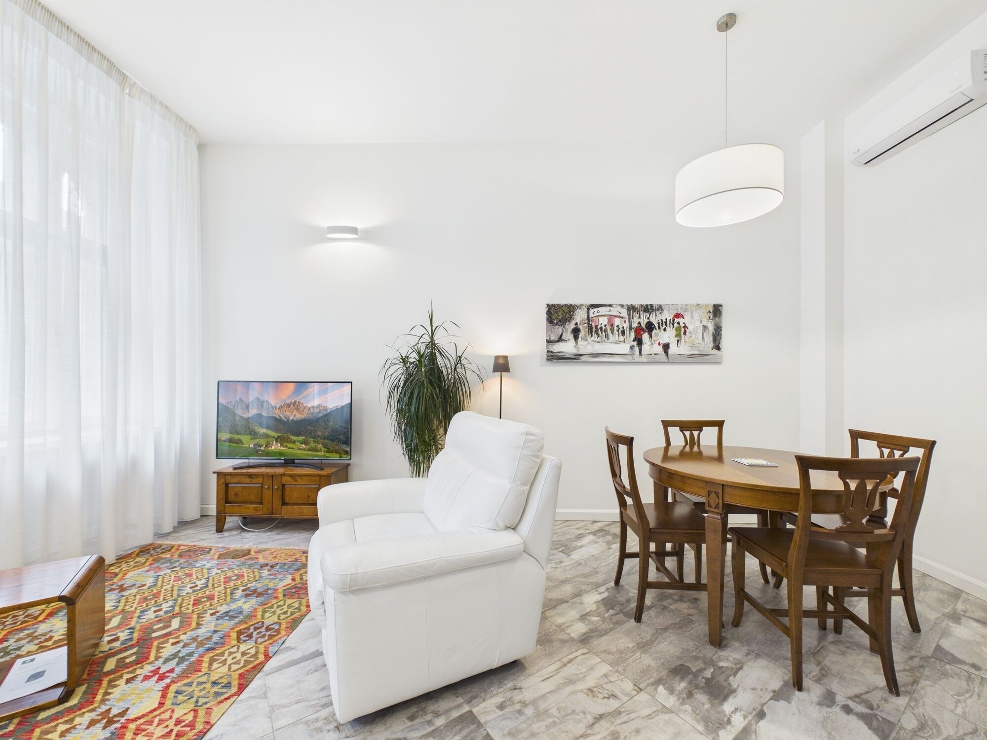 Un soggiorno moderno con un divano bianco, un tavolo da pranzo con sedie, una TV e un quadro appeso al muro.