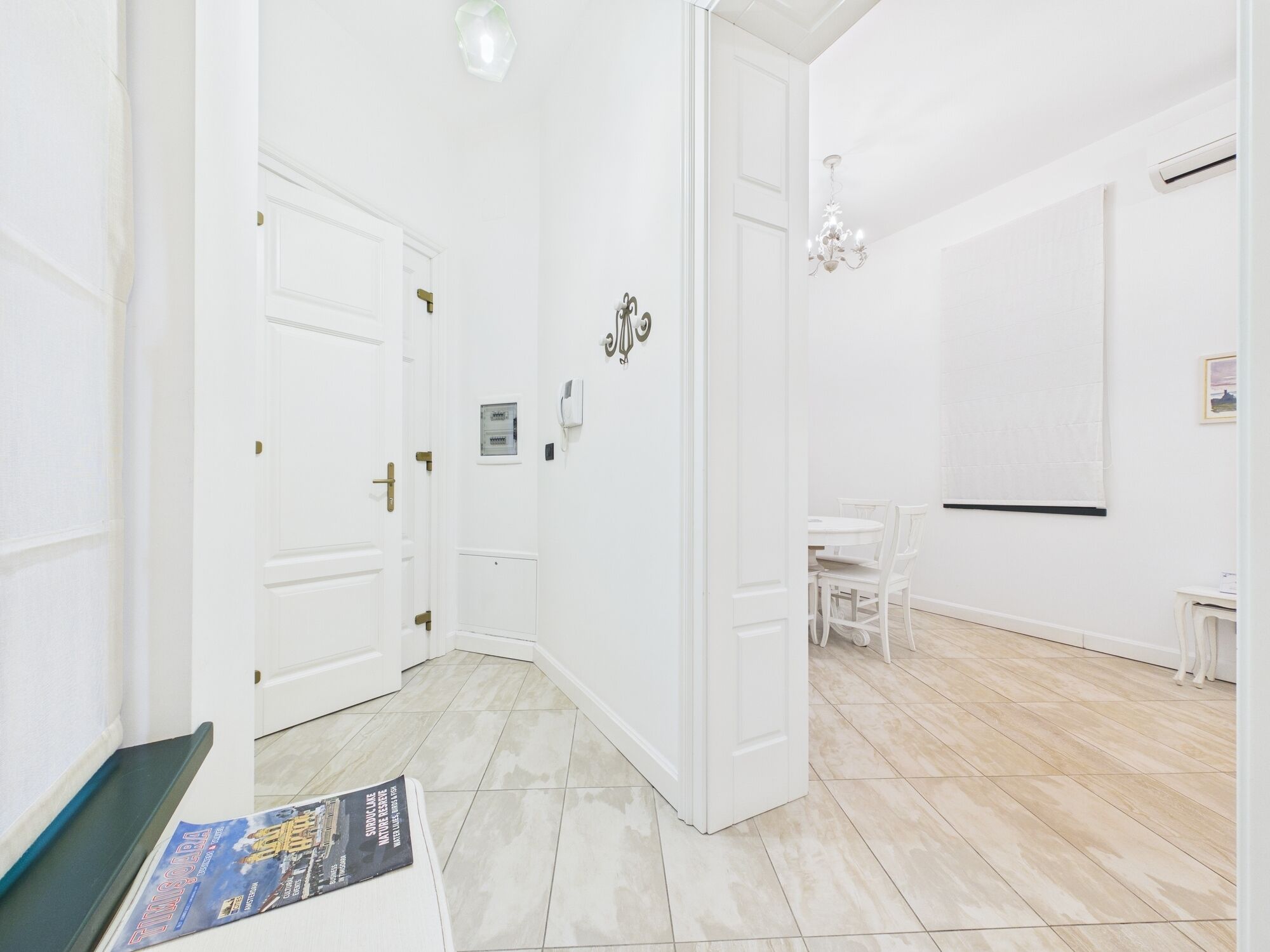 Ein Flur mit weißen Türen, ein weißes Esszimmer und eine Chandelüster.