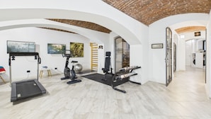 Een huisgymnasium met een loopband, een hometrainer en trainingsballen.