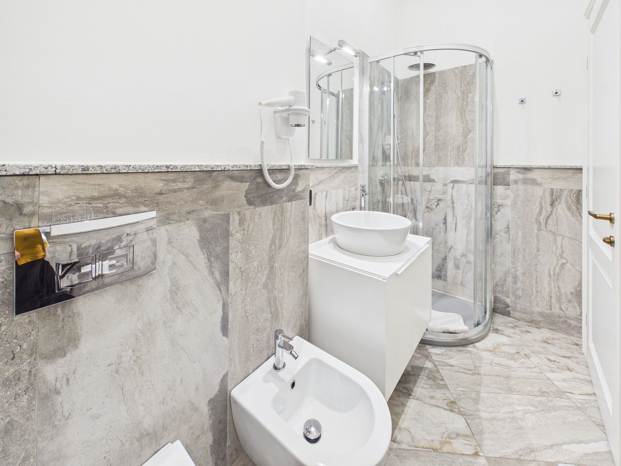 A modern bathroom with a bidet, a sink, and a glass-enclosed shower.