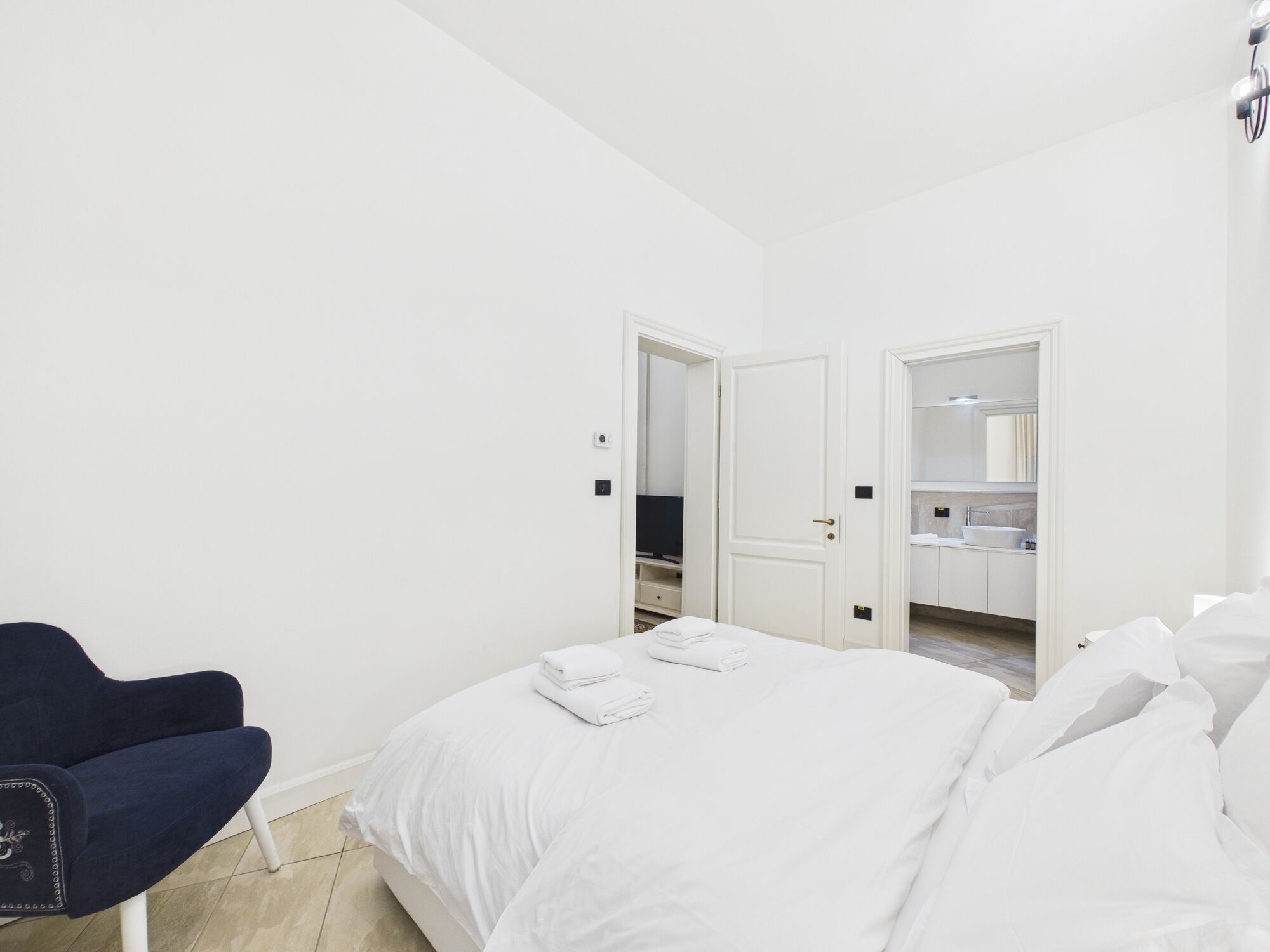 A hotel room with a bed, a chair, and a bathroom visible through an open door.