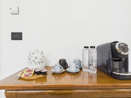 Una encimera de cocina con cafetera, hervidor, tetera, tazas y condimentos.