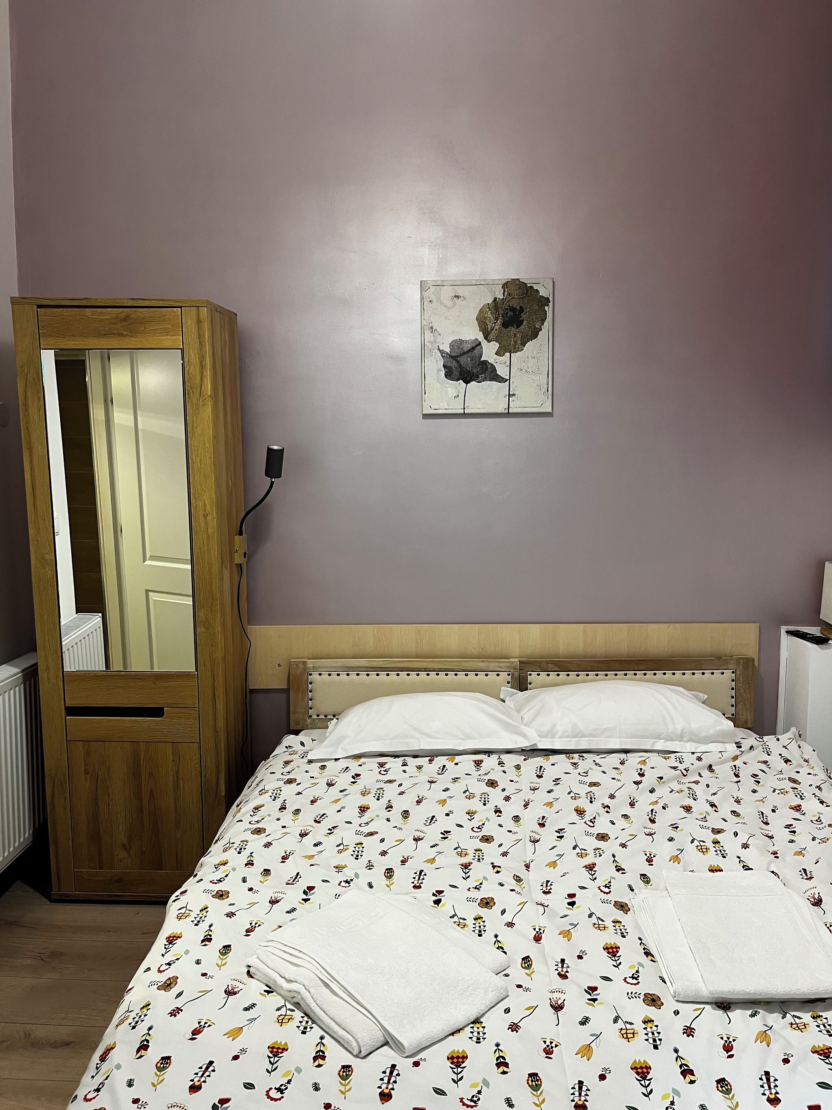 Ein Schlafzimmer mit einem Bett, einem Holzschrank, einer Wandmalerei und einer Heizung.