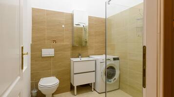 A compact bathroom with a toilet, sink, and washing machine.