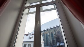 Uitzicht door een raam op een gebouw met een groot rondboogvenster en een met sneeuw bedekte kap.