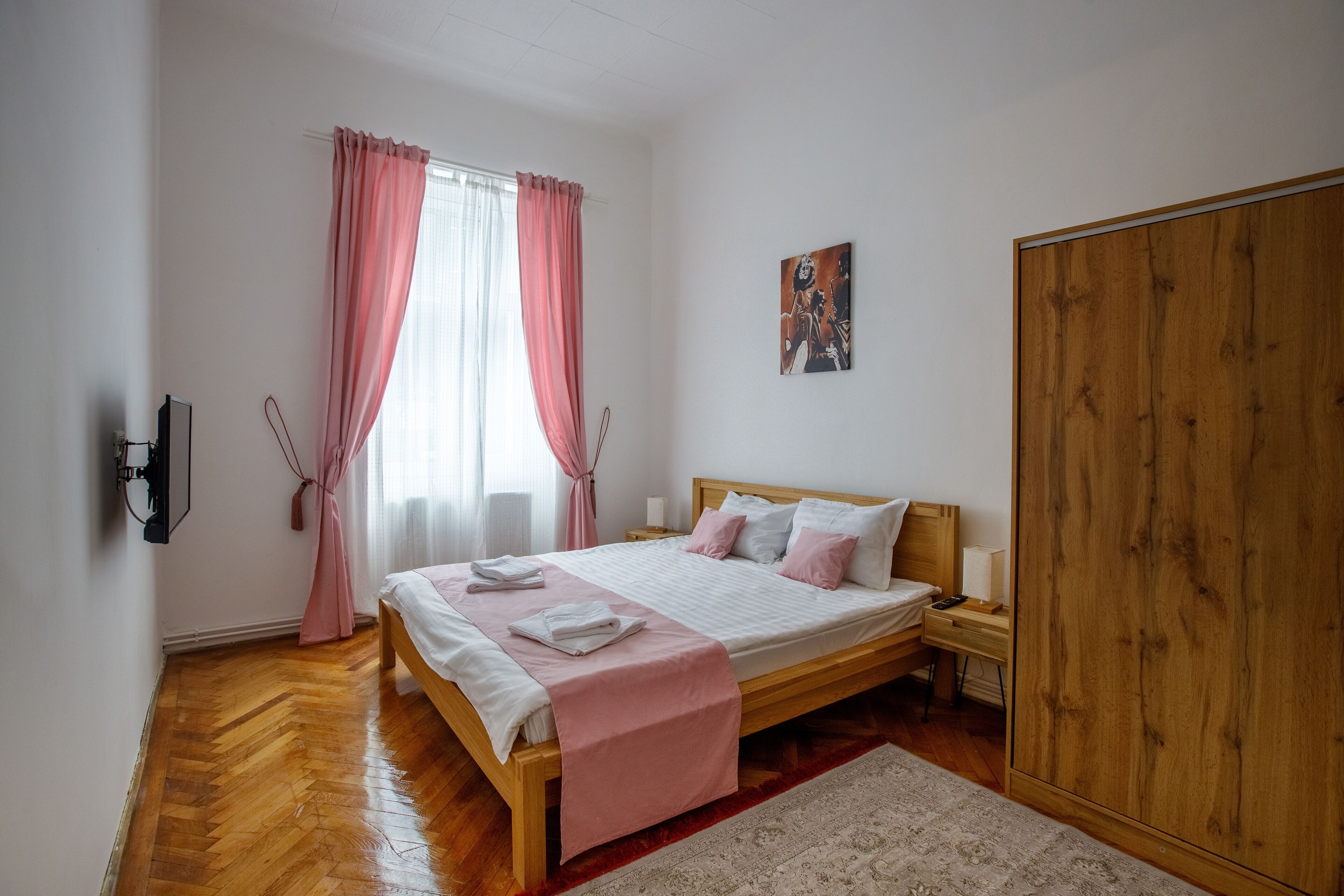 A bedroom with a wooden bed, a nightstand, a wardrobe, and a window with curtains.