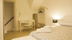 A bedroom with a bed, a desk, a chair, and a lamp.
