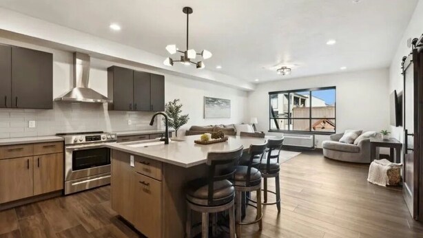 A modern kitchen with a central island, built-in oven, and stainless steel range hood.