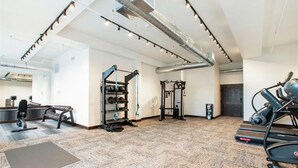 A gym with exercise equipment, a treadmill, and a yoga mat.