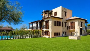 Une maison à deux étages avec une piscine, une façade en pierre et une pelouse bien entretenue.