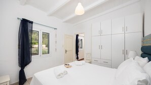 Un dormitorio con una cama grande, paredes blancas y un armario.