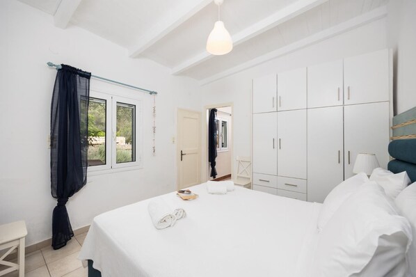 Quarto com cama grande, paredes brancas e um guarda-roupa.