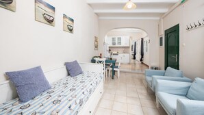 Un salón acogedor con un sofá, una zona de comedor y una cocina al fondo.