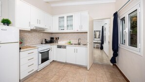 Una cocina compacta con armarios blancos, estufa y lavamanos.