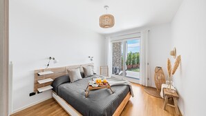 Un dormitorio moderno con cama, mesitas de noche, lámpara de noche, ventana con vistas y una bandeja con productos para el desayuno.