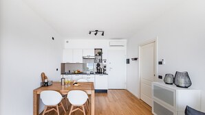 Una cocina moderna con armarios blancos, una mesa de comedor de madera y dos sillas blancas.