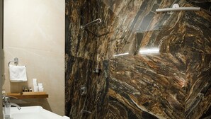 A bathroom with a marble wall, a sink, and a shower. - Firebrick Garnet House (Gurugram)