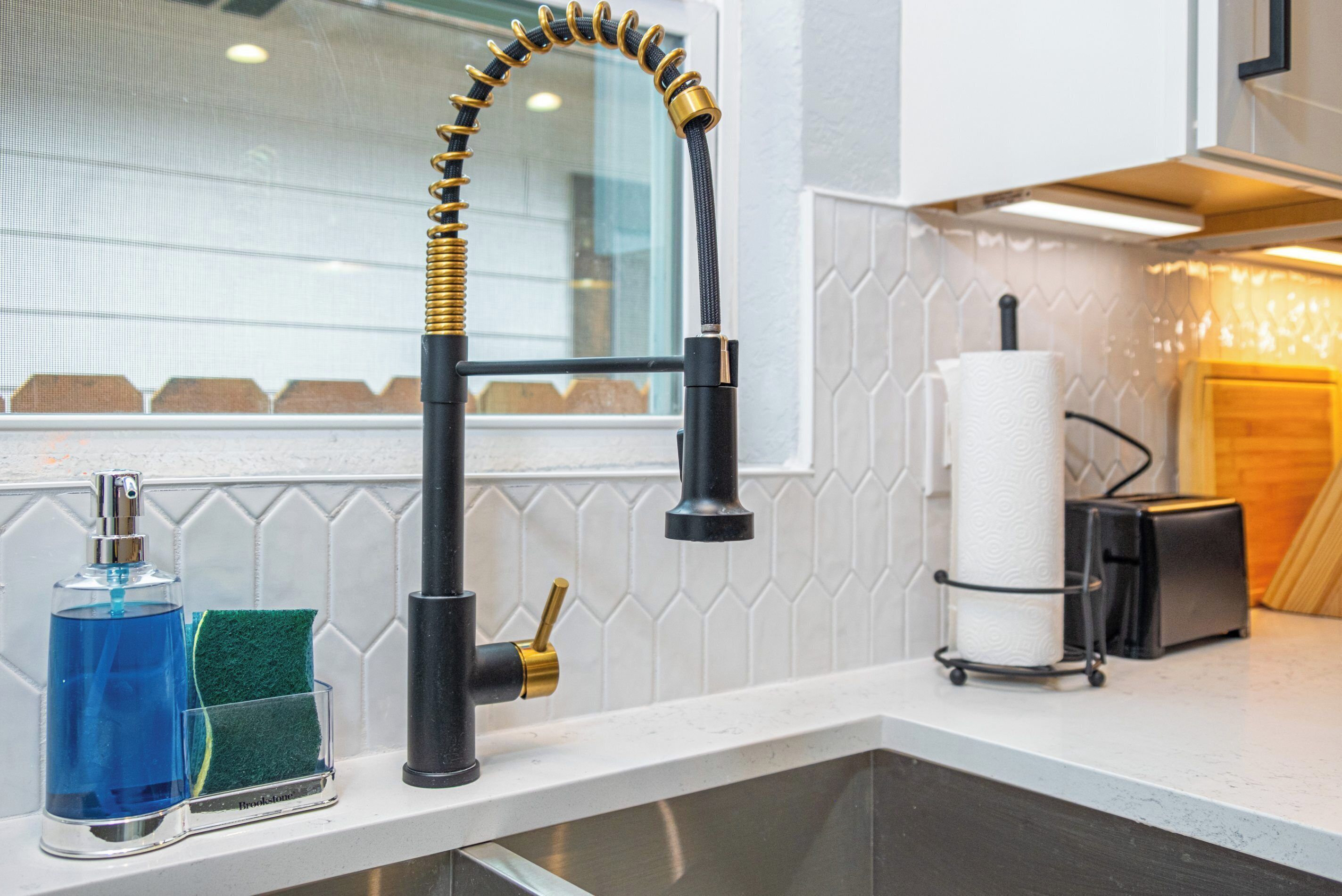 Una cocina con un grifo moderno, un dispensador de jabón y un escurreplatos.