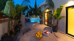 Una terrazza esterna con piscina, sedie a sdraio e un tavolo con frutta e riviste.