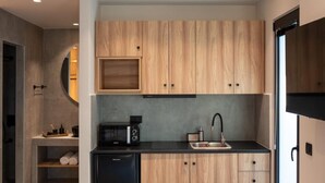 Una cucina moderna con mobili in legno, un frigorifero nero, un forno a microonde e un lavello.