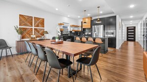 Una cocina moderna con una mesa y sillas de madera, un horno empotrado y un refrigerador.
