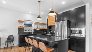 Una cocina moderna con una isla grande, electrodomésticos de acero inoxidable y armarios negros.