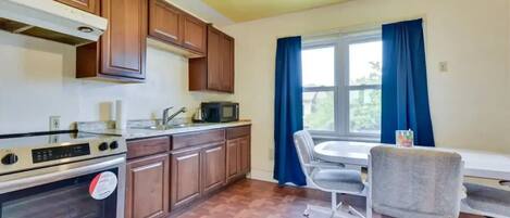 A kitchen with wooden cabinets, a microwave, and a dining area with a table and chairs.