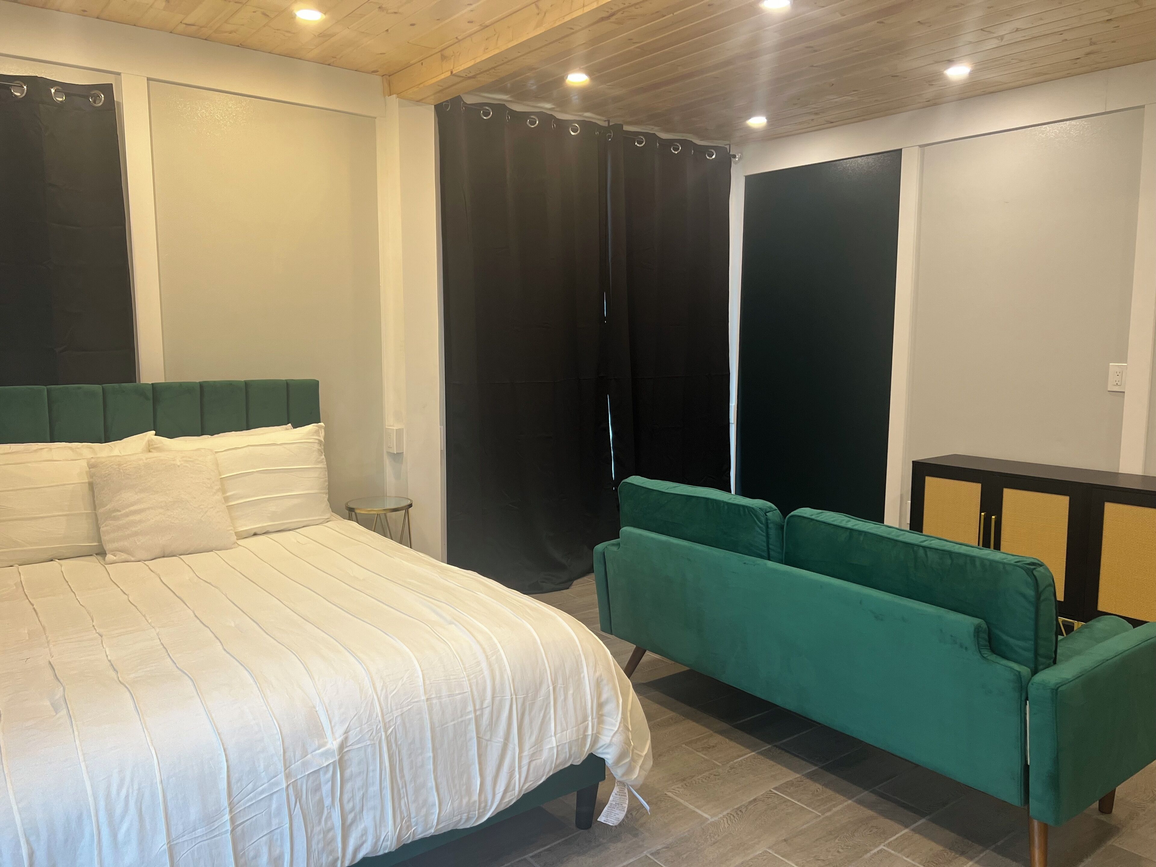 Een slaapkamer met een bed, een groene bank, een garderobe en een klein tafeltje.
