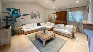 A spacious living room with a sectional sofa, a wooden coffee table, and a large potted plant. - Mas de Peyre (Le Beaucet)
