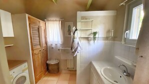 A compact bathroom with a washing machine, a bathtub, and a sink. - Mas de Peyre (Le Beaucet)