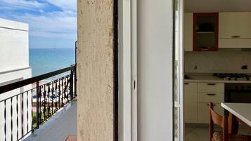 Ein Balkon mit Meerblick und einer Küchenzeile inklusive Schränke und einem Stuhl.